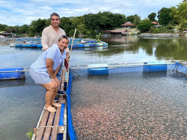 Two people next to red tilapia ponds