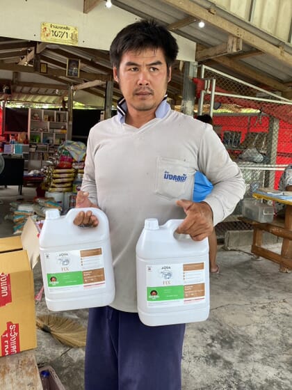 Fish farmer holding bottles of Aqua Fix seaweed extract