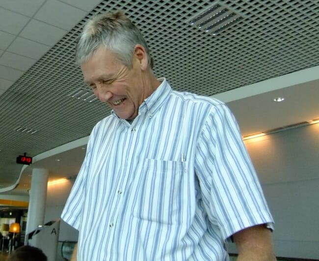 A man in a stripped shirt smiling.