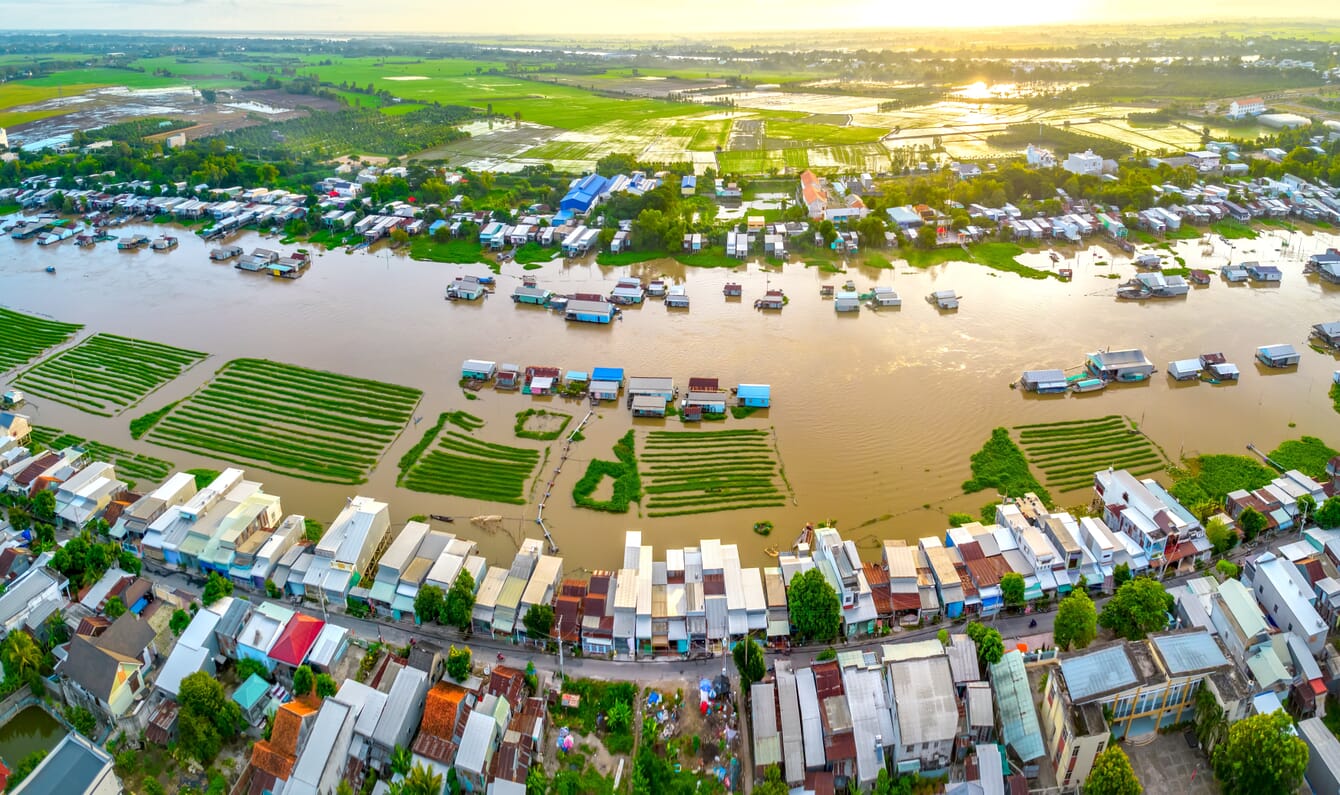 Vista aérea de casas ao longo de uma margem de rio inundada.
