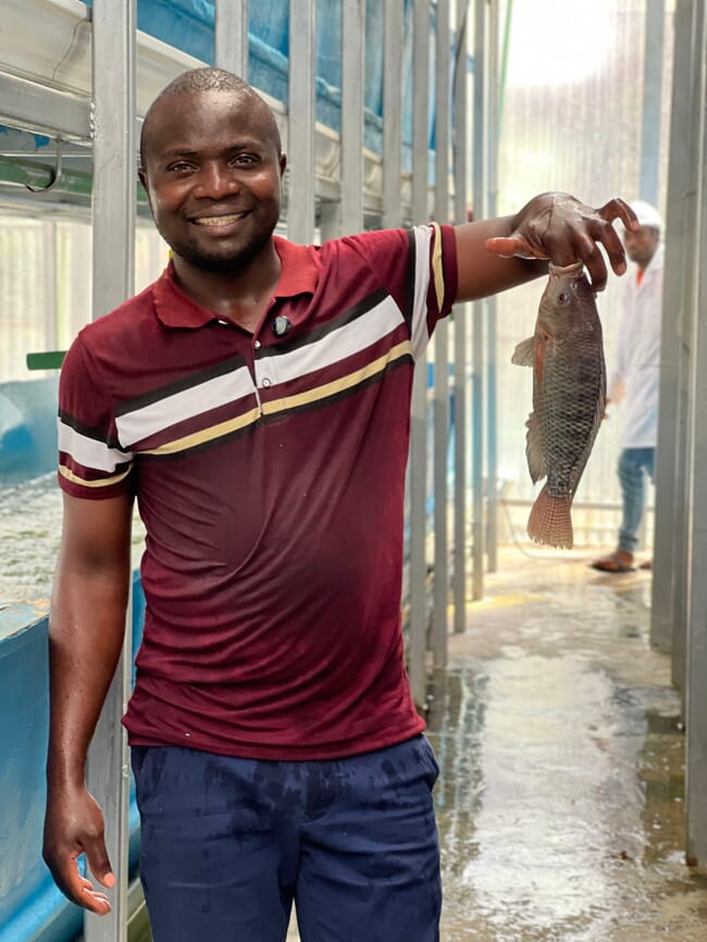 An entrepreneur holding a fish grown in his innovative farming system.