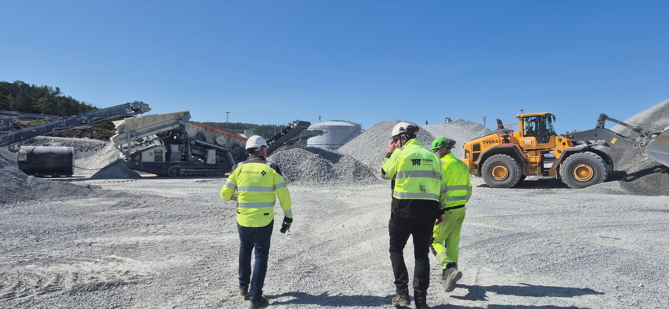 Three people in hi-viz jackets at a construction site.