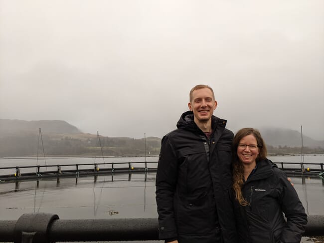 two people standing on a salmon farm