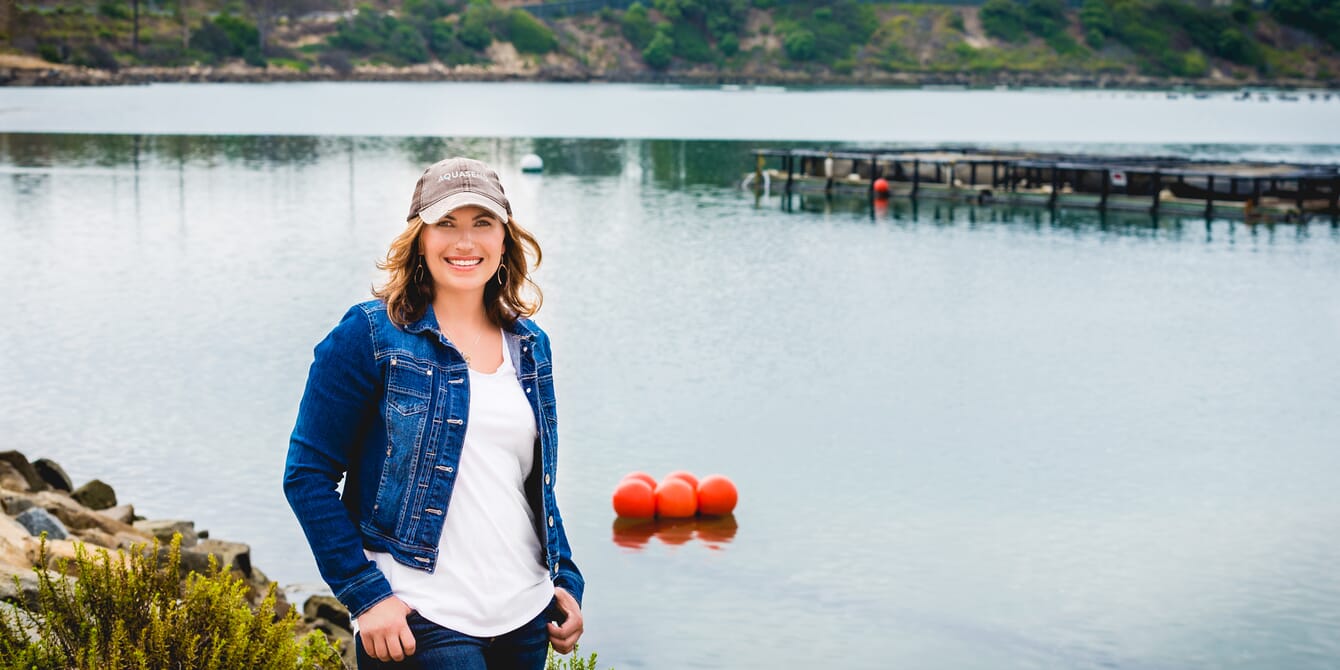 A woman standing in front of a lake.