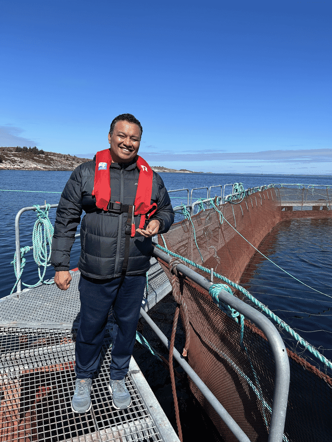 A man standing beside a fish pen.