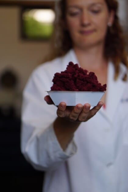 woman holding red seaweed powder