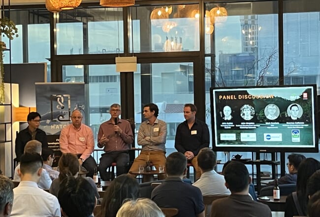 Four men on a panel talking to an audience