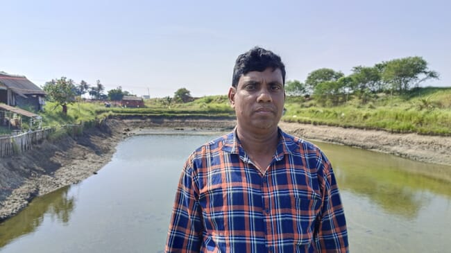 A man standing in front of a shrimp pond.