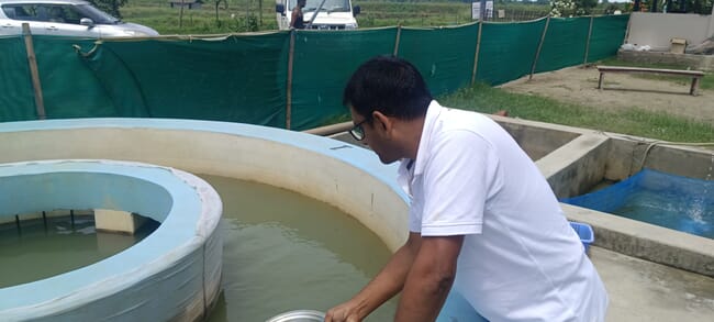 A farmer inspecting his circular freshwater aquaculture ponds.
