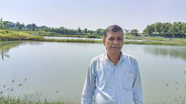 A man standing in front of a shrimp pond.