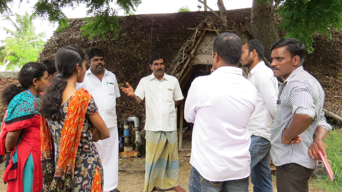 A man talking to shrimp farmers in India.