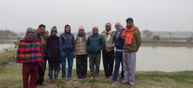 group of men standing near a flooded field