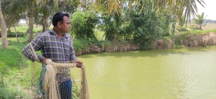 man holding a net next to a fish pond