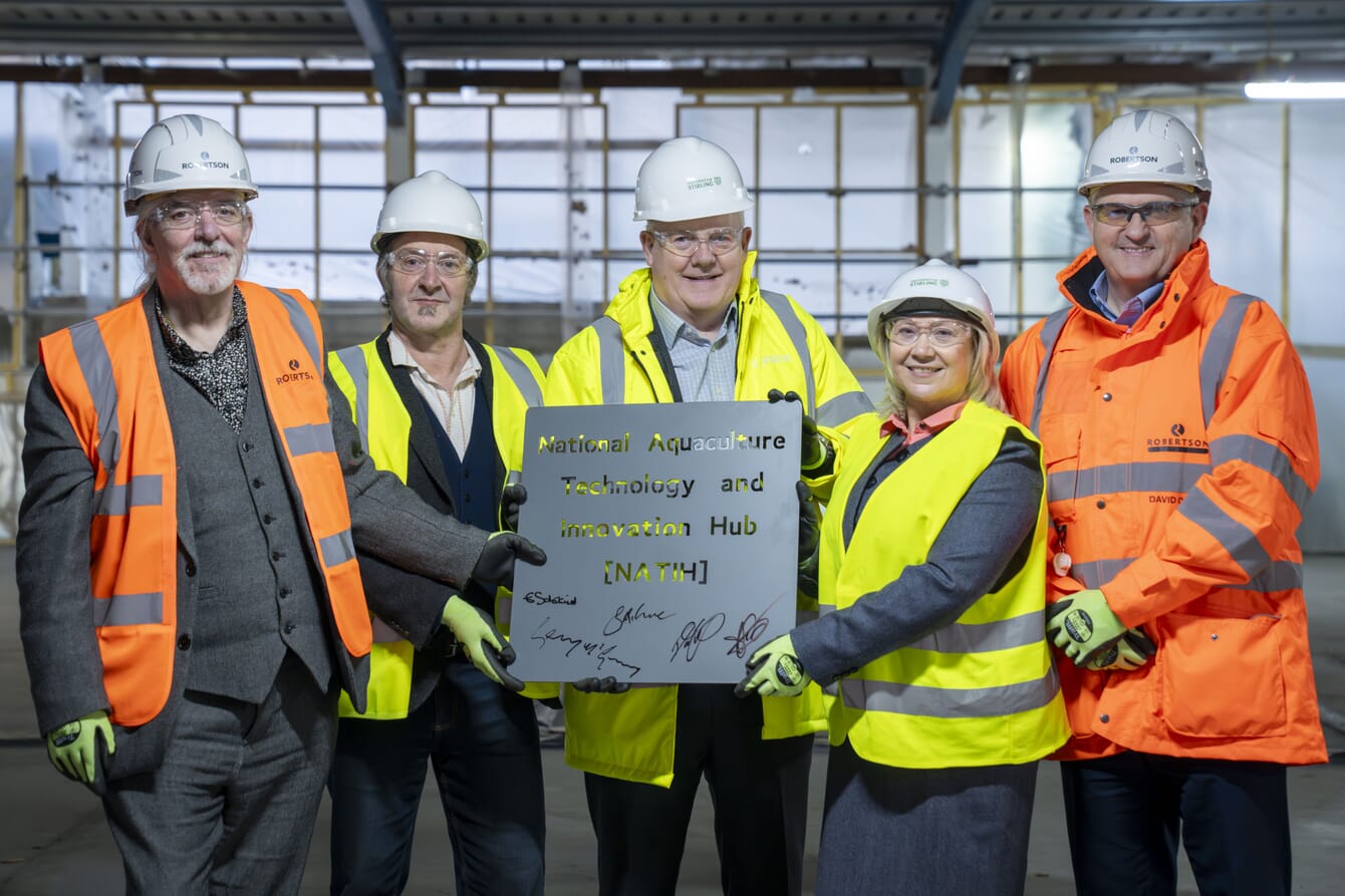 A group of people posing with a signed plaque.