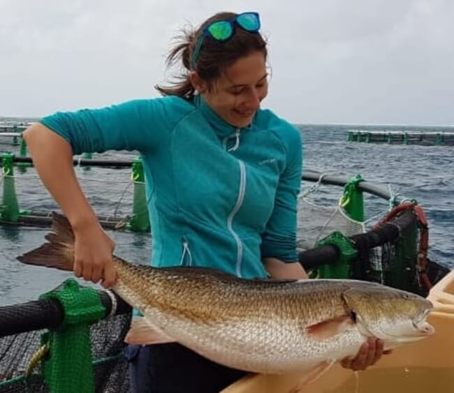 A woman holding a harvest size aquaculture fish in Mauritius.