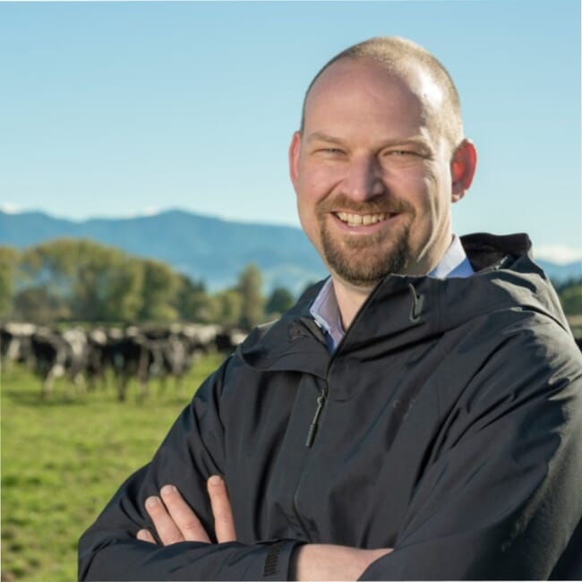Headshot of a man in a field of cattle.