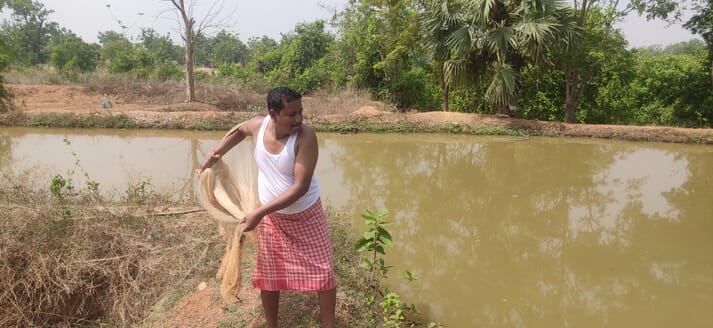 man throwing a net into a pond