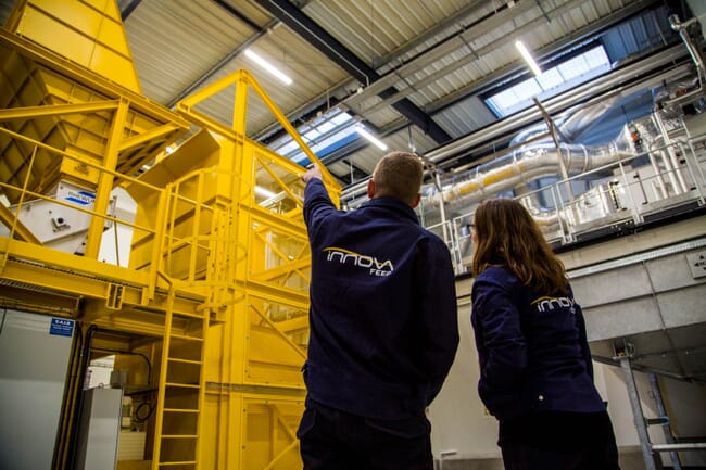 Two farm technicians in front of processing equipment