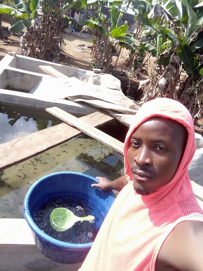 man holding a bucket near concrete ponds