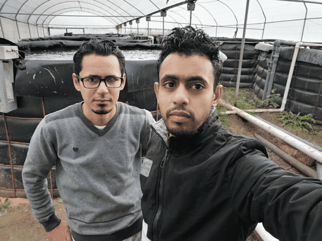 two men standing in front of water tanks