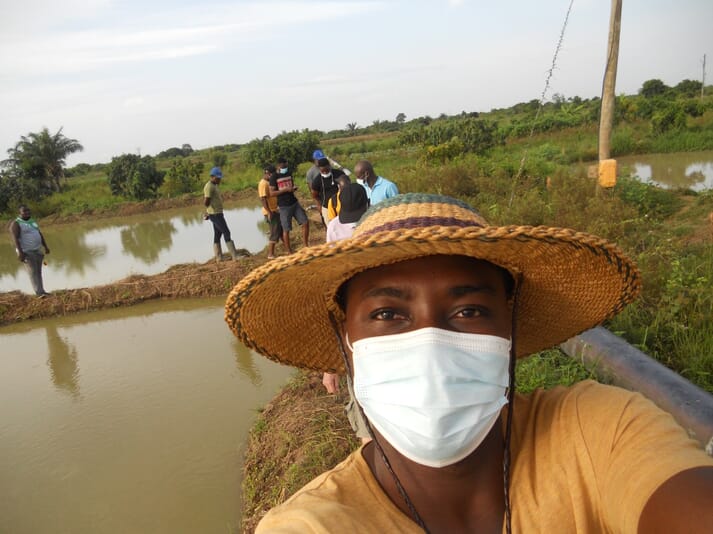 Man in a facemask standing next to two outdoor fish ponds
