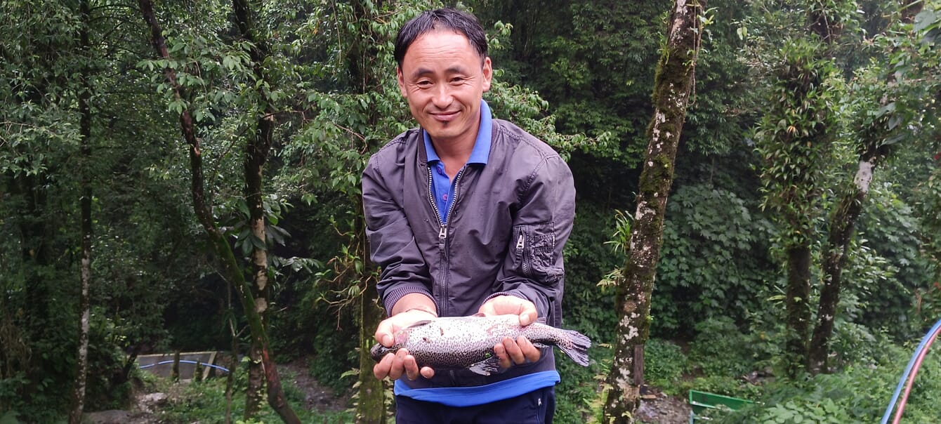 Portrait of Prem Kumar Rai holding a rainbow trout
