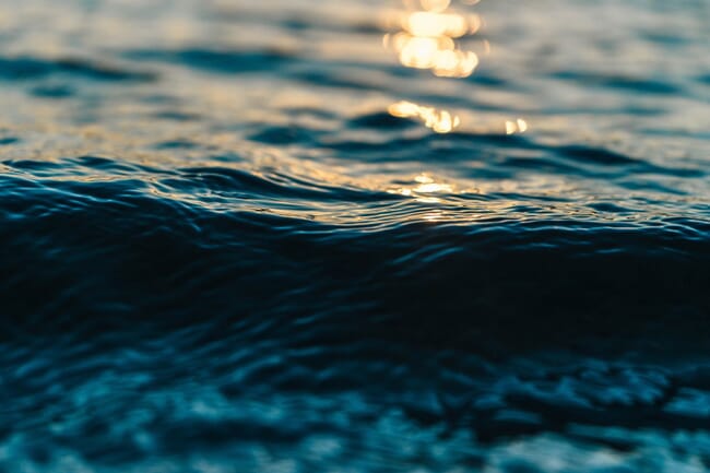 Primer plano de una ola de agua en la que se refleja la luz.