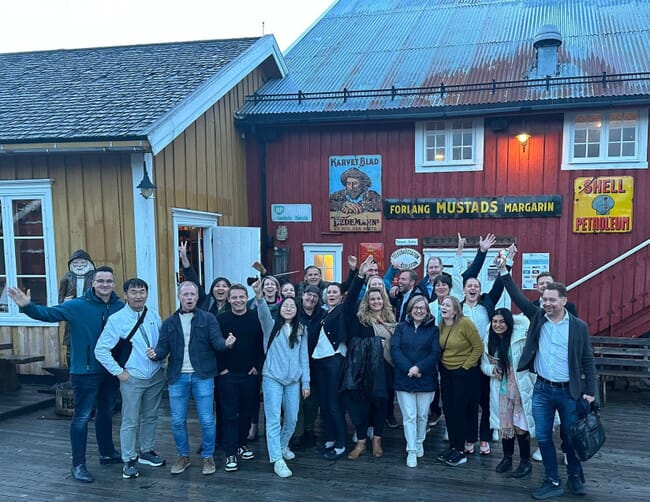 A group photo in front of a traditional Norwegian clapboard building.