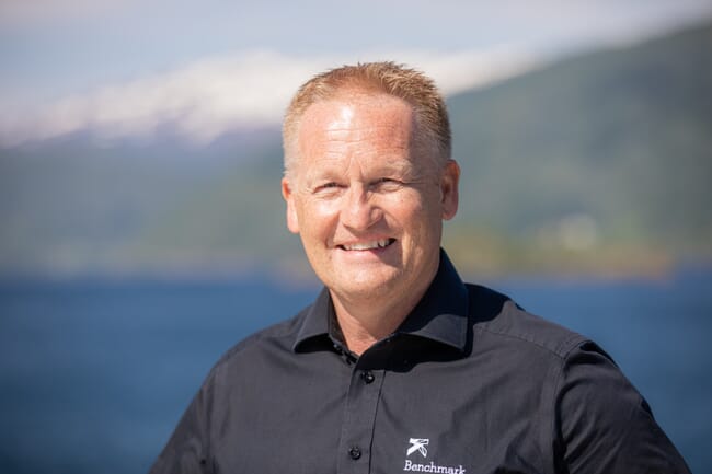 Man smiling infront of a fjord.