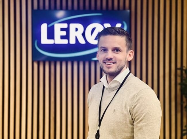 A man standing in front of a company logo.