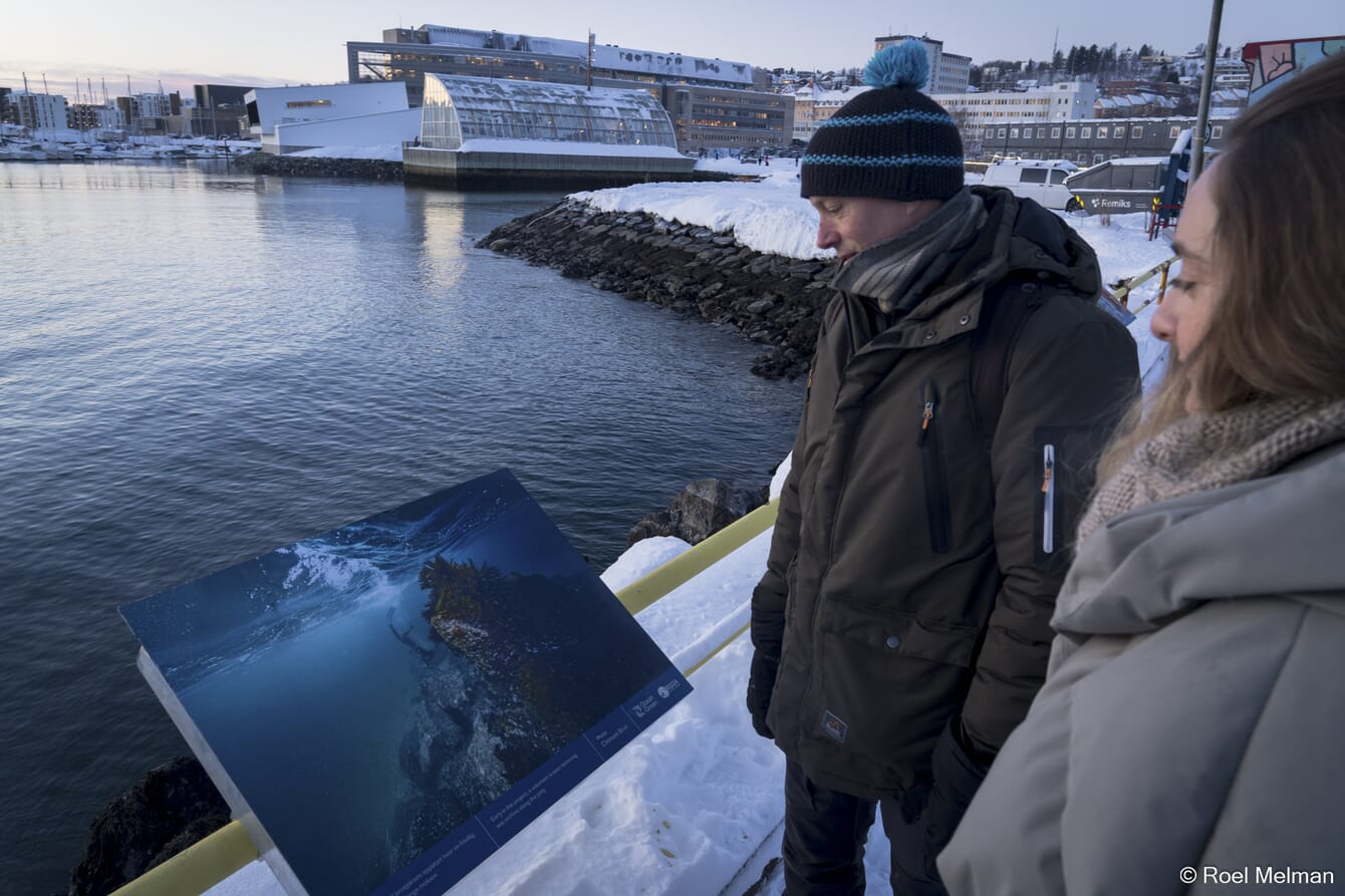 Two people looking at an outdoor exhibition under the snow in the Arctic circle.