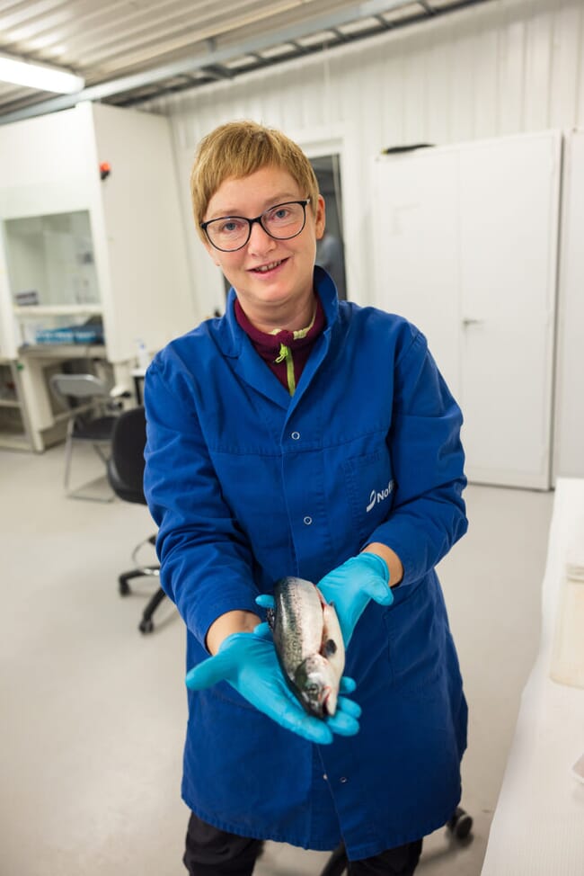 A woman holding a dead fish.