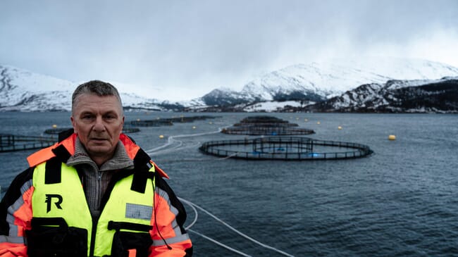 man standing with aquaculture net pens in the background