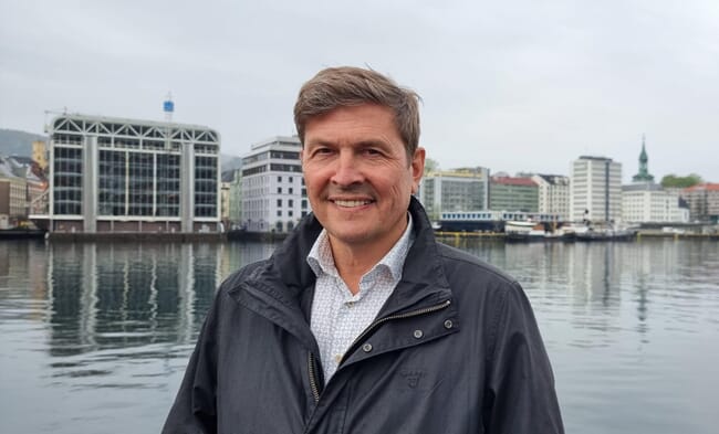 Headshot of a man with water and buildings in the background