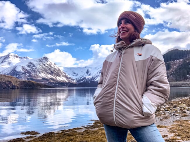 a woman standing in front of snowy coastal mountains