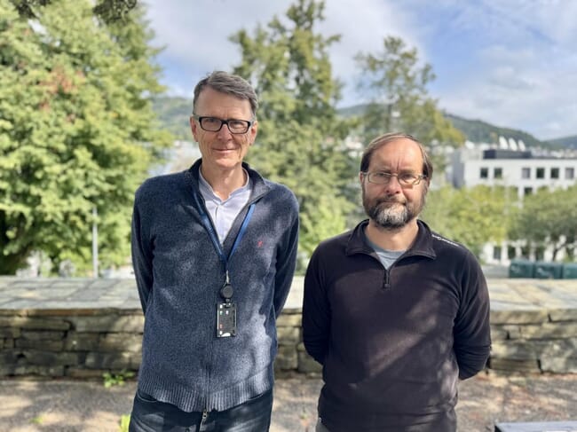 Two scientists standing in a university park on a sunny day.