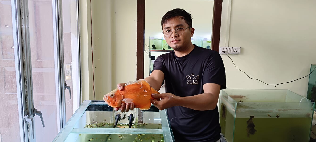 man holding a fish above a tank