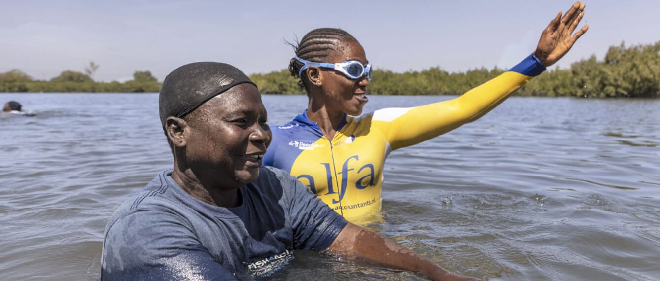 One woman teaching another woman how to swim in the sea.