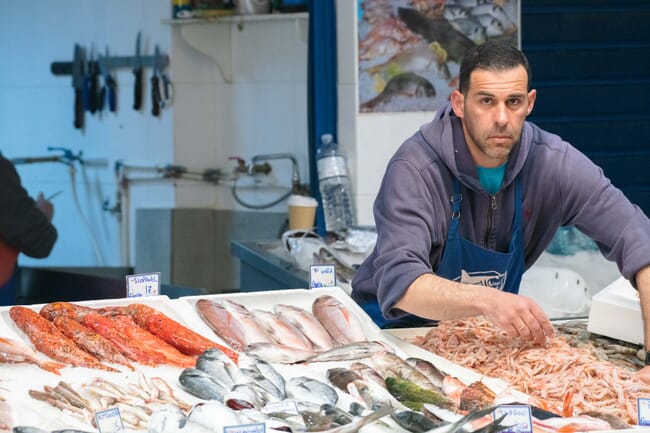 a fishmonger at work behind his display of seafood