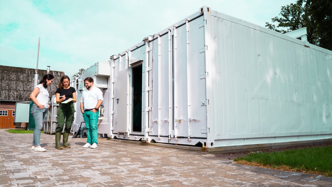 People standing next to shipping container RAS system