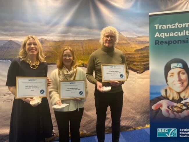 Three people holding award certificates.