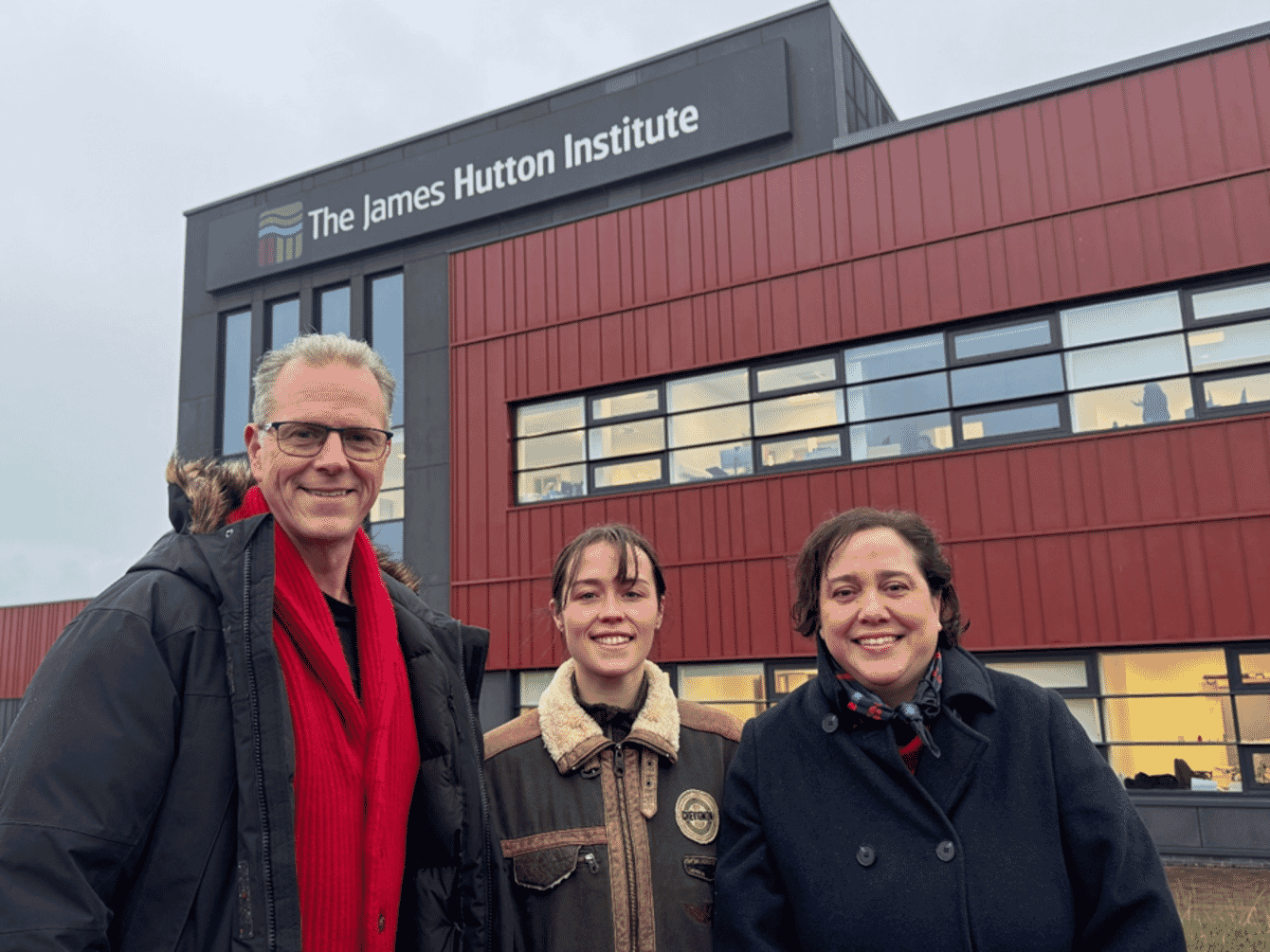 Three people standing infront of a building in Scotland.