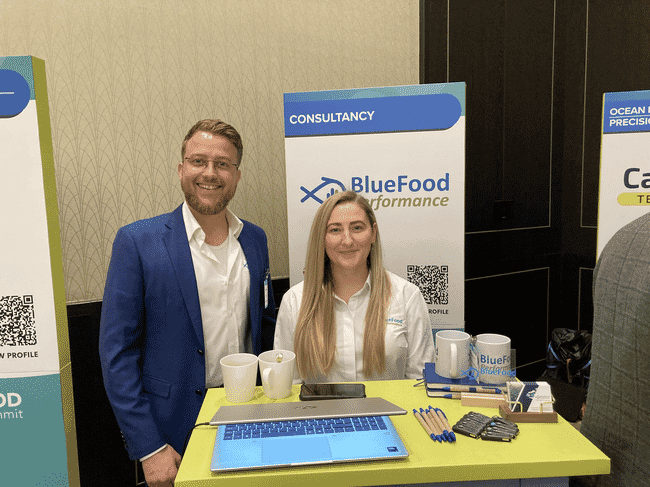 Two people standing behind a trade show stand.