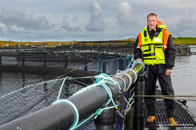 a man standing on a salmon pen