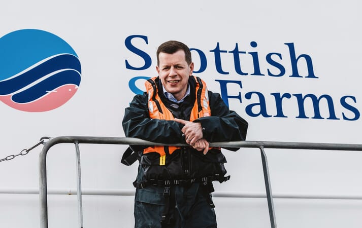Man standing in front of the Scottish Sea Farms logo