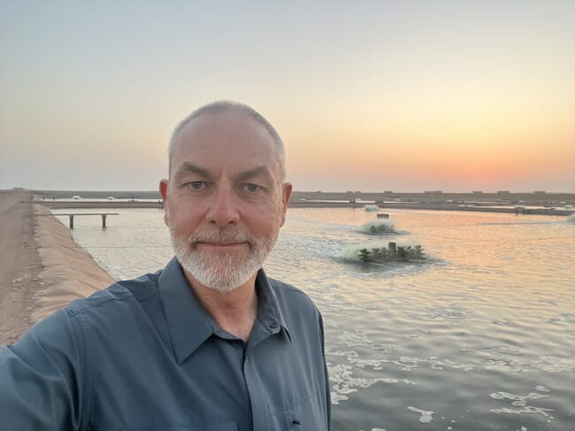 A man standing in front of a shrimp pond