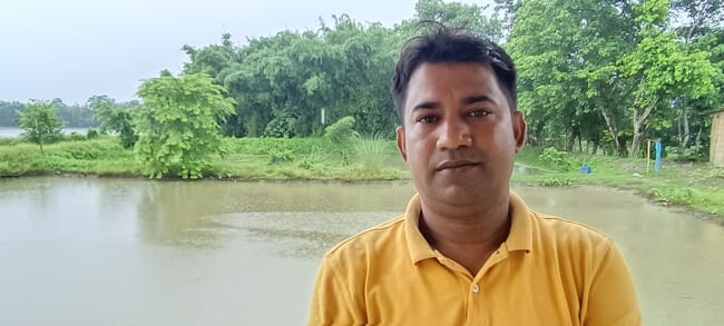 A man standing in front of a pond.