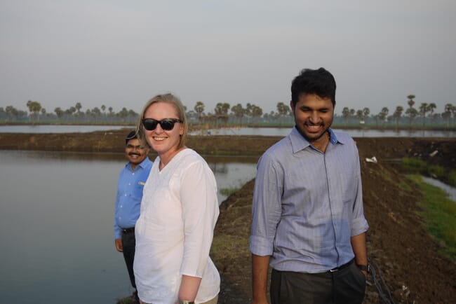 Three people beside a shrimp pond.