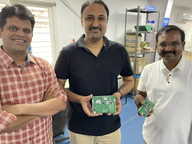 Three men holding up circuit boards.