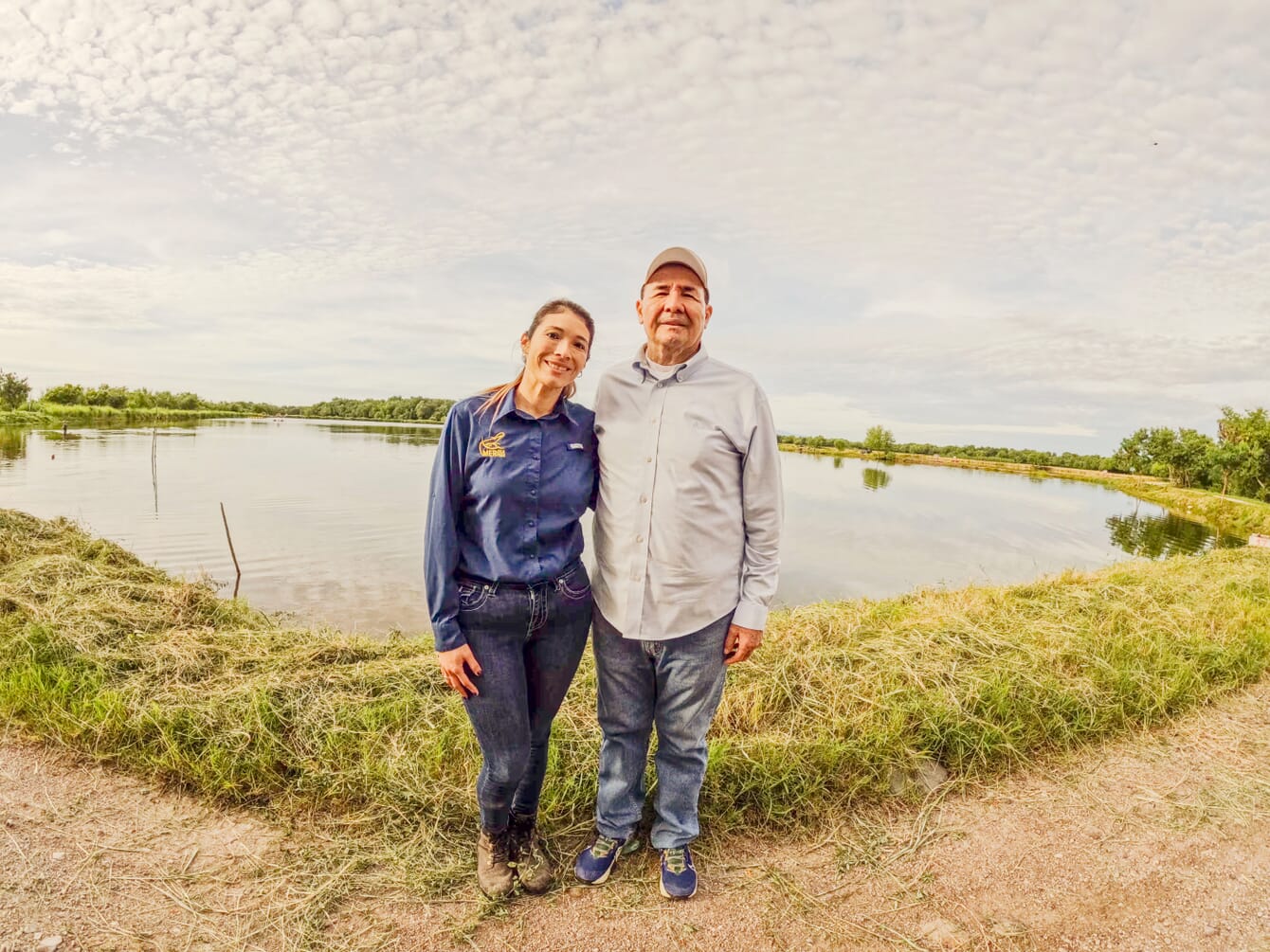 Two people beside a shrimp pond